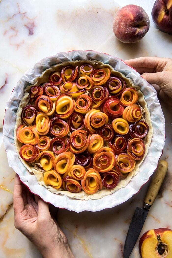 未加工的甜桃子上升的照片玫瑰色馅饼用在照片前的手用手在烘烤前