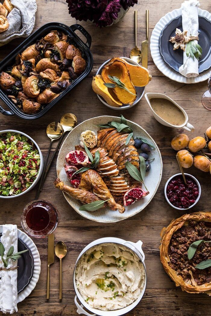 头顶上的感恩节餐桌上有火鸡、土豆、填料和鲜花的照片