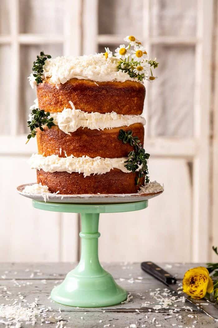 柠檬椰子赤裸蛋糕旁边有角度的照片与在蛋糕立场和花在蛋糕立场和花的鞭子乳酪