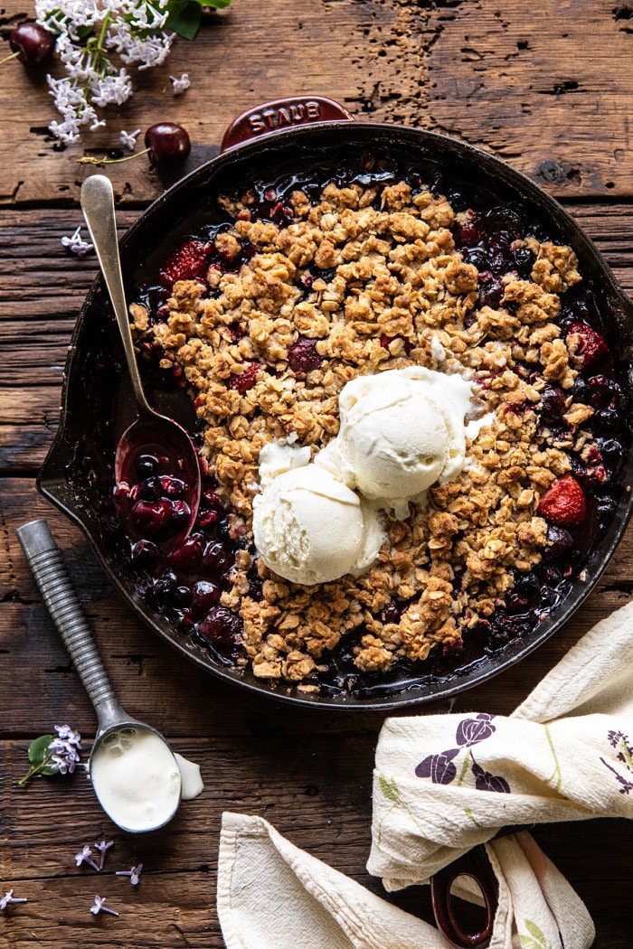 黄油樱桃莓果脆皮酥皮煎锅顶上的照片与冰淇凌的在酥脆和匙子在煎锅