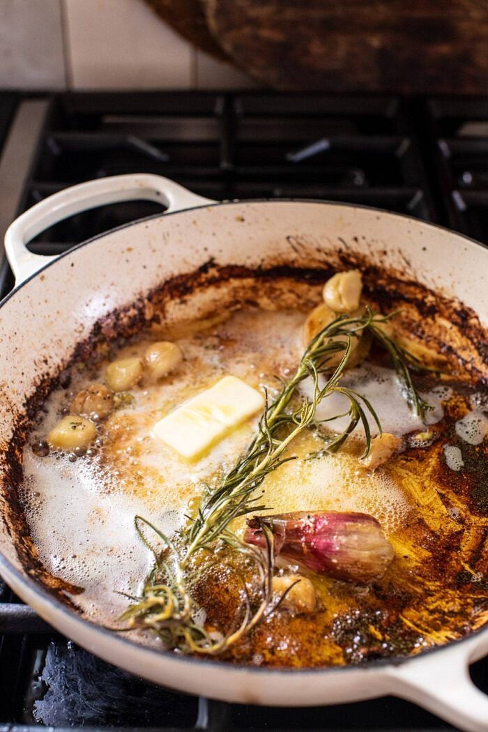 在炉子煎锅的黄油，大蒜，青葱和迷迭香侧面角度的照片