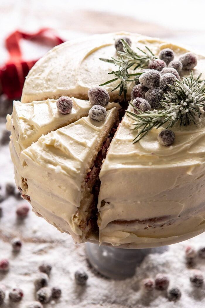 旁边有角度的关闭白色圣诞节蔓越桔层数蛋糕照片与2片切开的蛋糕