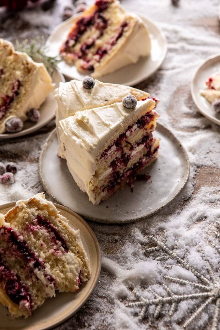 白色圣诞蔓越莓层蛋糕片站在甜点盘上的侧面照片