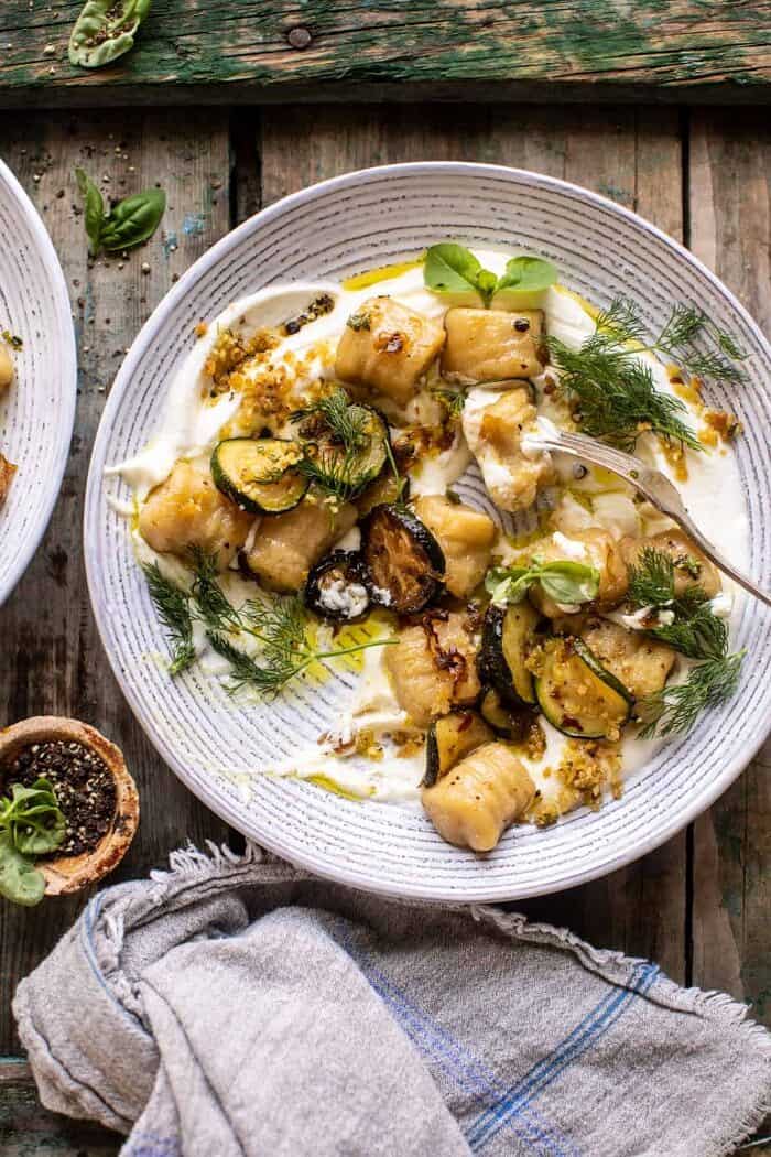 花椰菜gnocchi架空的照片与酥脆夏南瓜和鞭打的山羊乳酪和叉子在碗用花椰菜gnocchi吃了